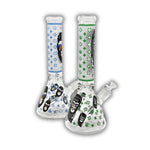 Clear glass beaker bong with monkey face graphics, designer-inspired repeating pattern print, cannabis leaf accents, and colored neck designs in blue and green.