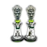 Decorative glass bong featuring a tribal warrior head sculpture, clear chamber body, and matching green accent details with removable bowl.