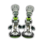 Artistic glass dab rig featuring an ancient queen head sculpture, engraved tribal details, and matching decorative bowl accents.