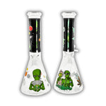 Clear glass beaker bong featuring green alien artwork, galaxy and planet graphics, cannabis leaf accents, and black space-themed neck print.
