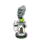 Decorative glass bong featuring a tribal warrior head sculpture, clear chamber body, and matching green accent details with removable bowl.