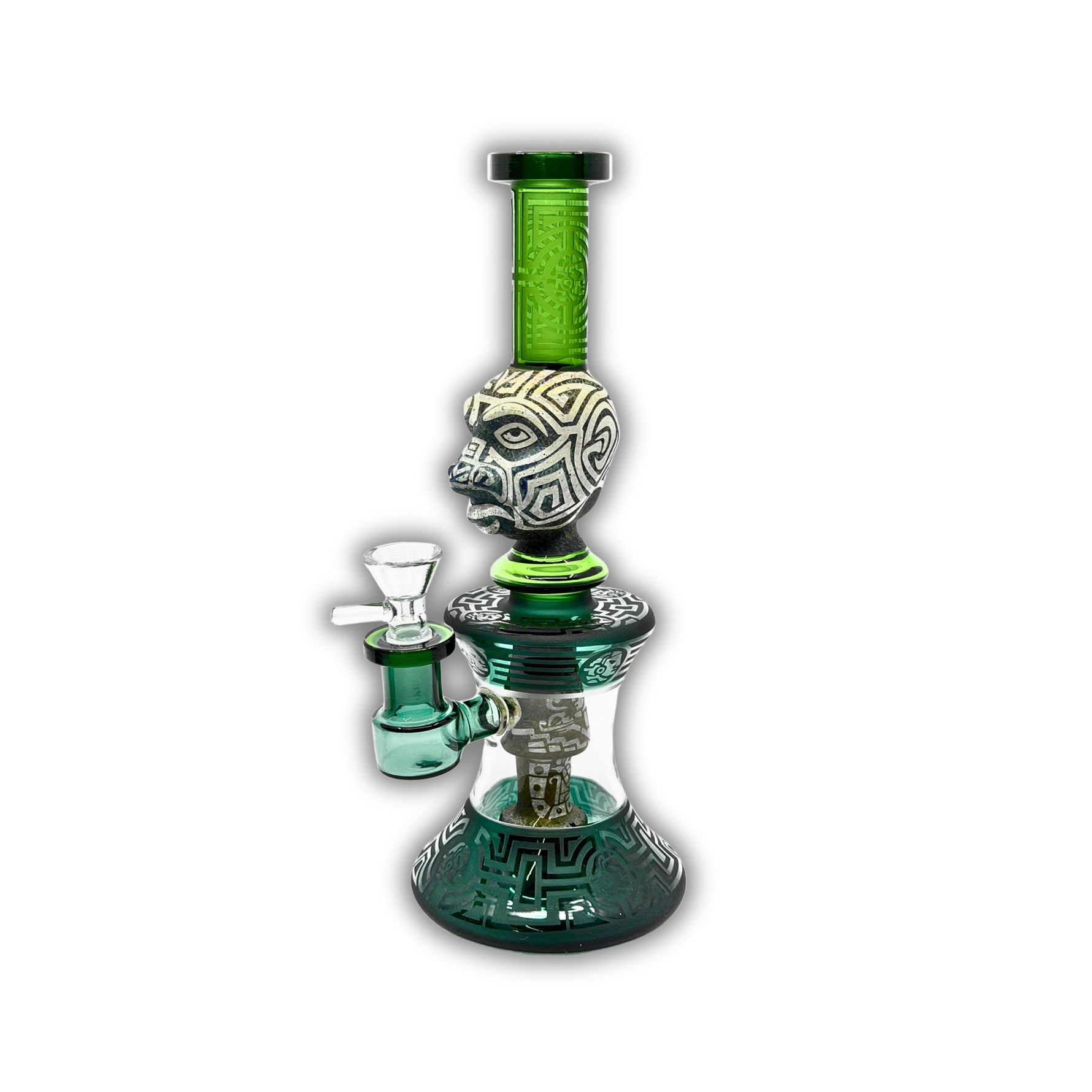Decorative glass water pipe featuring carved tribal face artwork, frosted etched patterns, emerald green neck tubing, and detailed geometric base accents.