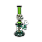 Decorative glass water pipe featuring carved tribal face artwork, frosted etched patterns, emerald green neck tubing, and detailed geometric base accents.