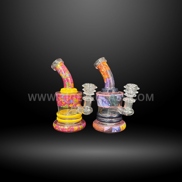 Set of two colorful mini dab rigs with bold pink, orange, and purple patterns. Compact wholesale glass rigs for oils and concentrates.