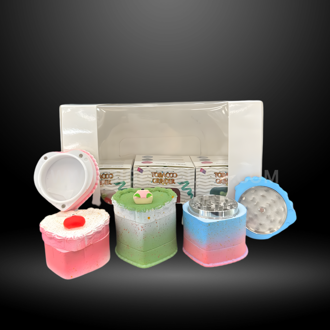 Colorful cake-shaped herb grinders in heart and square designs with detailed frosting tops and layered colors. Fun novelty grinders for smoking accessories