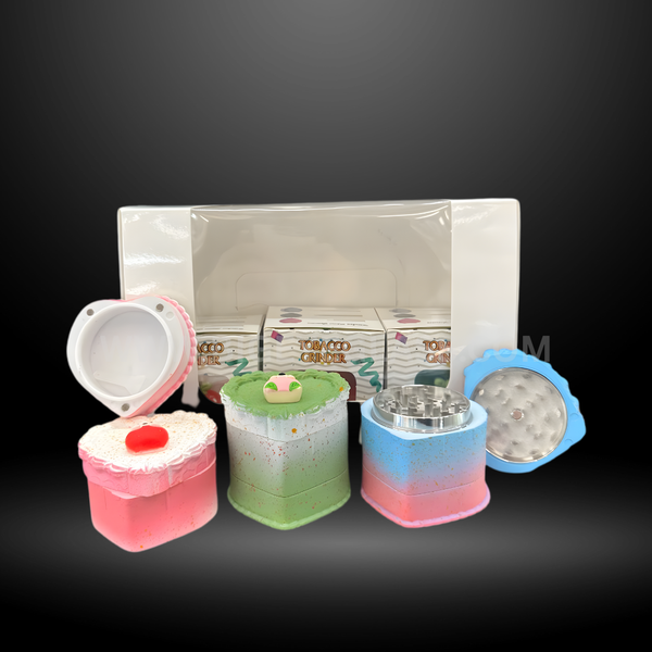 Colorful cake-shaped herb grinders in heart and square designs with detailed frosting tops and layered colors. Fun novelty grinders for smoking accessories