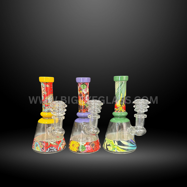 Set of three colorful patterned glass beaker bongs with floral and abstract designs. Durable wholesale water pipes for head shops and distributors.