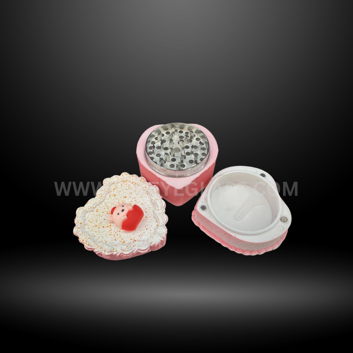 Pink cake-shaped herb grinders in heart and square designs with detailed frosting tops and layered colors. Fun novelty grinders for smoking accessories